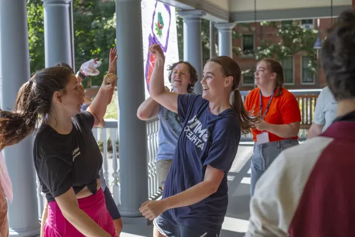 Student leaders dance on the porch of a house during move-in