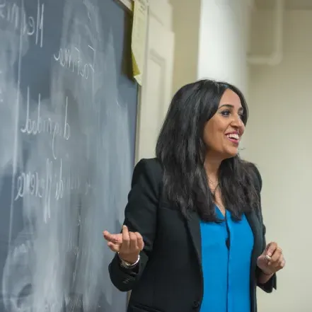 A professor pointing to a chalkboard.